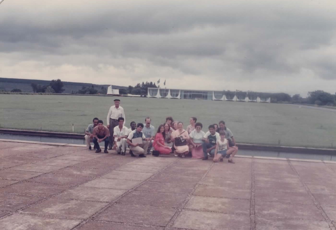 Grupo de missionários posando diante do Palácio da Alvorada, em Brasília, sob céu nublado.