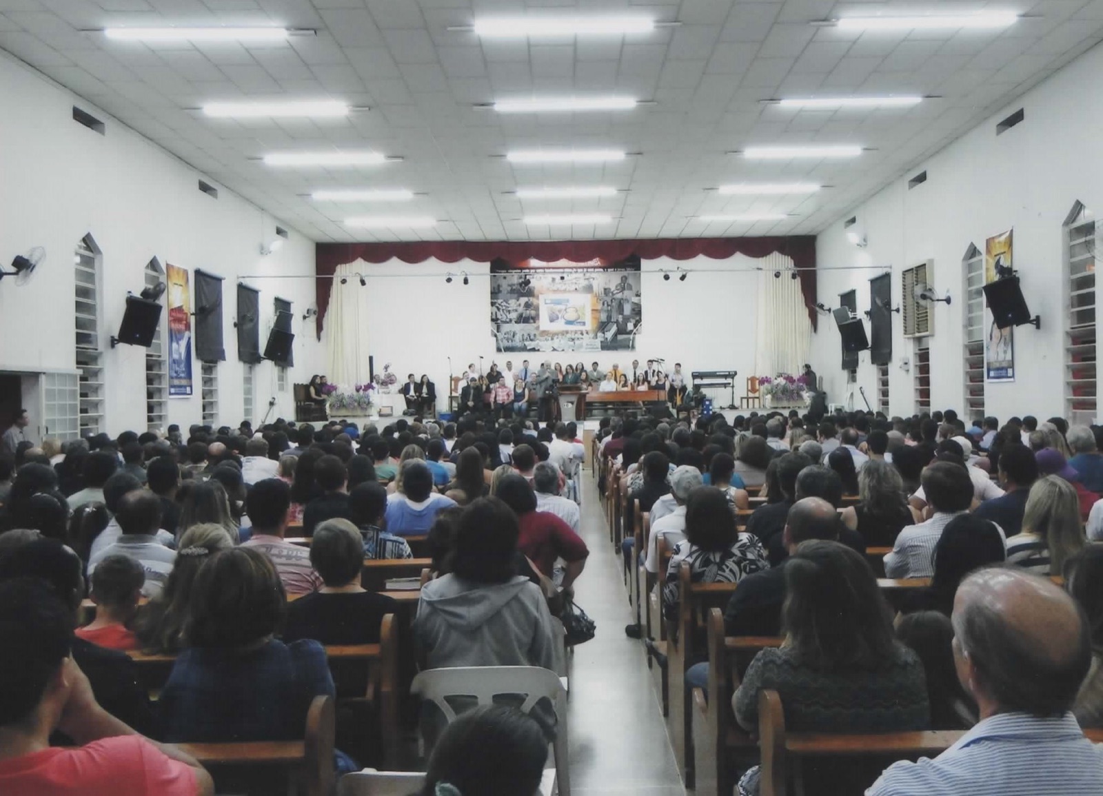 Templo lotado, visto do fundo, com centenas de pessoas sentadas e o coro ao fundo.