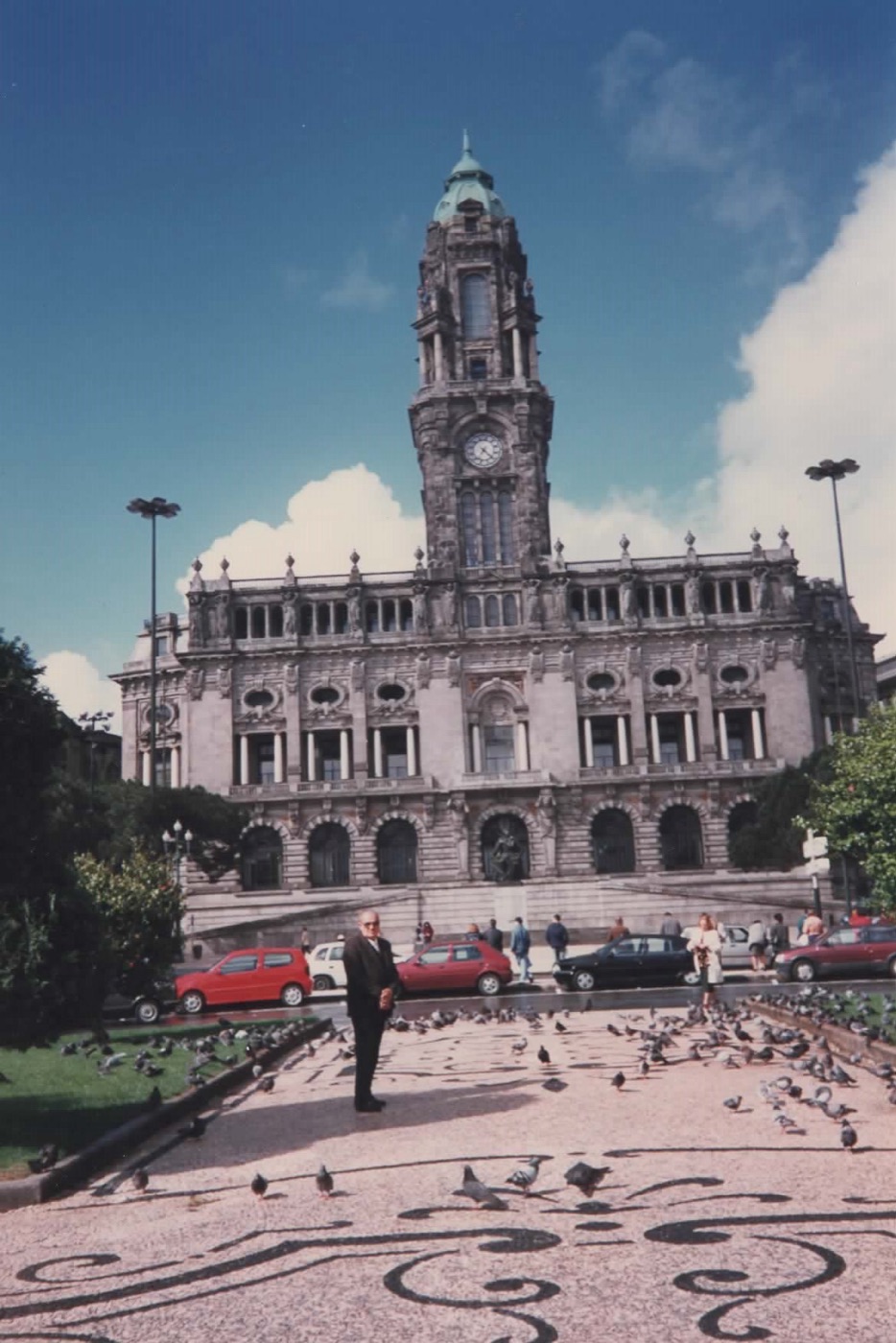 Antenor em pé na praça da Câmara do Porto, em Portugal, cercado de pombos.